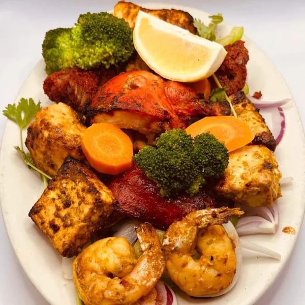 A platter of Indian House tandoori chicken, paneer, shrimp, broccoli, carrots, and lemon.